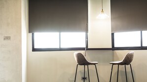 Two bar stools with a light fixture above them, positioned in front of a window with blinds. - Seven77 (Tainan)