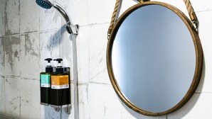 A bathroom with a shower, a round mirror with a rope handle, and two glass cups on a shelf. - Seven77 (Tainan)
