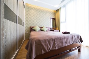 Comfortable bed with a wooden frame, patterned wallpaper, and a large mirror above.