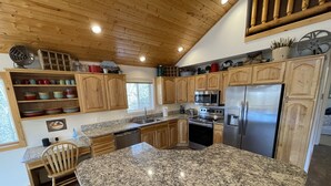 Una cocina con armarios de madera, encimeras de granito, un refrigerador de acero inoxidable y un horno empotrado.