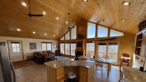 Una cocina amplia con una isla grande, techo de madera y varios ventanales.