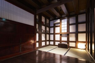 Una habitación japonesa tradicional con suelo de tatami, puertas correderas shoji y bajo techo de madera.