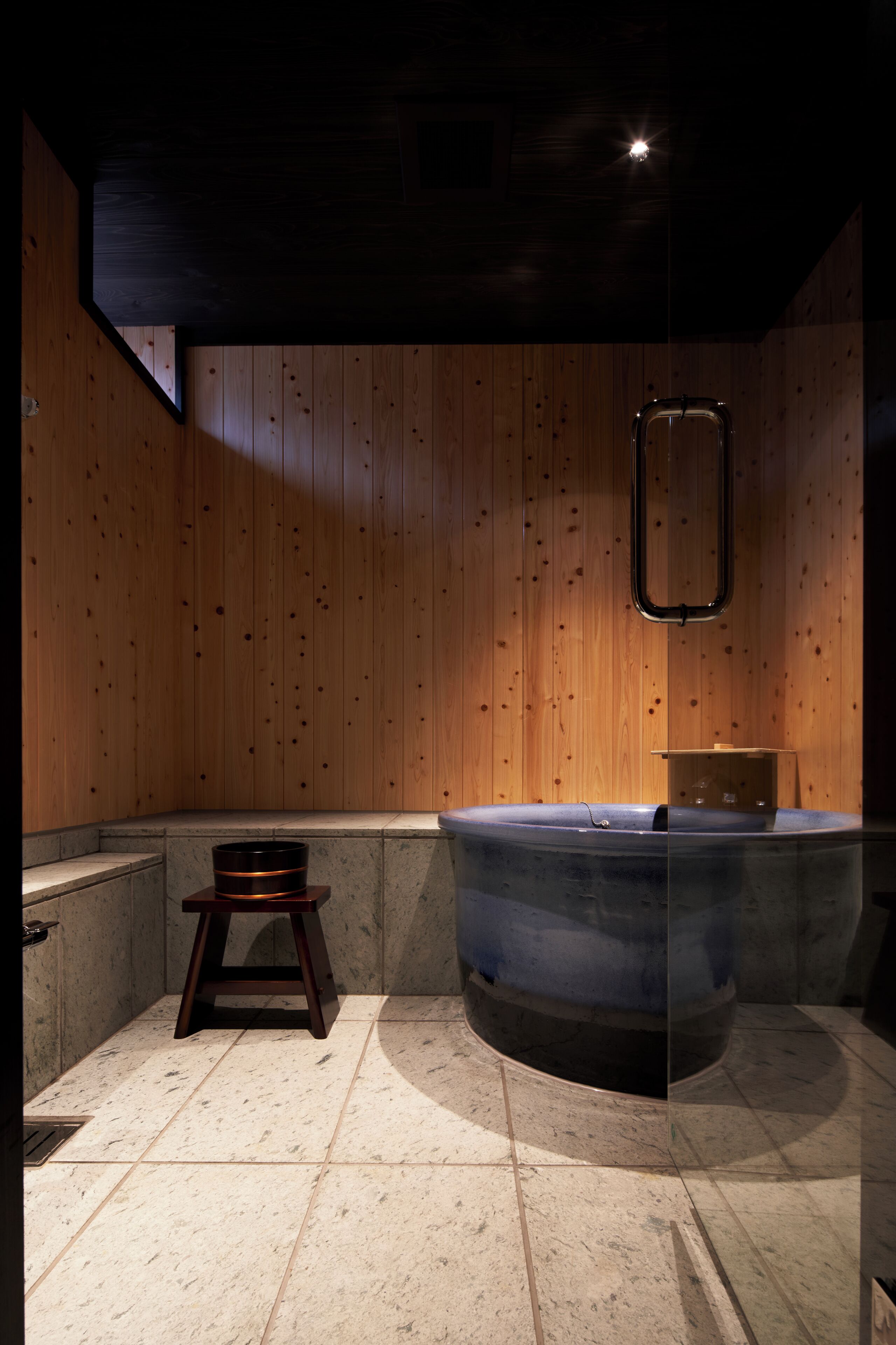 Une salle de bain moderne avec des murs en bois, une baignoire et un petit tabouret.