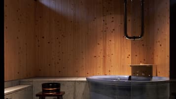 A modern bathroom with wooden walls, a bathtub, and a small stool.