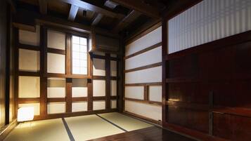 A traditional Japanese room with tatami flooring, sliding doors, and a wooden ceiling.