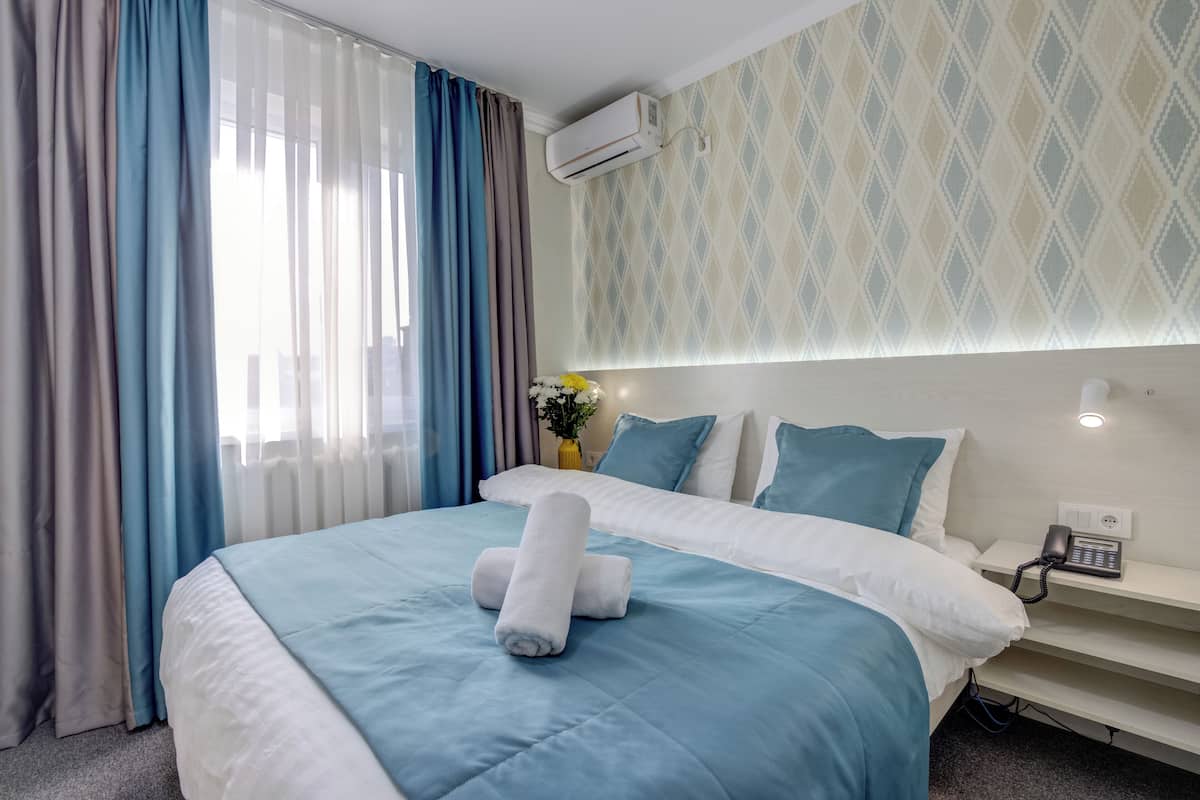 Una habitación de hotel con cama, mesita de noche, teléfono y aire acondicionado instalado en la pared.
