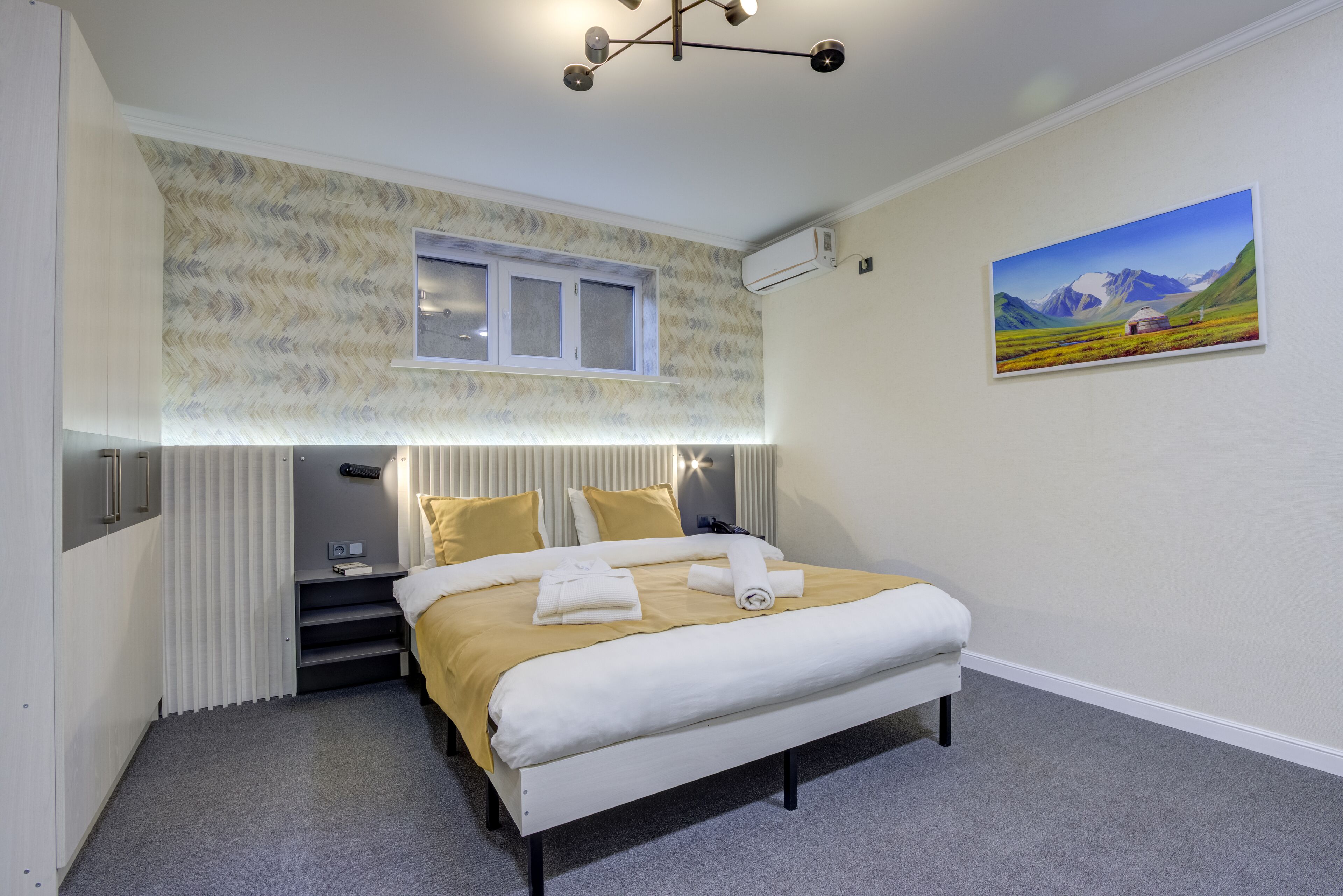 Een slaapkamer met een bed, een raam, een schilderij en een radiator.