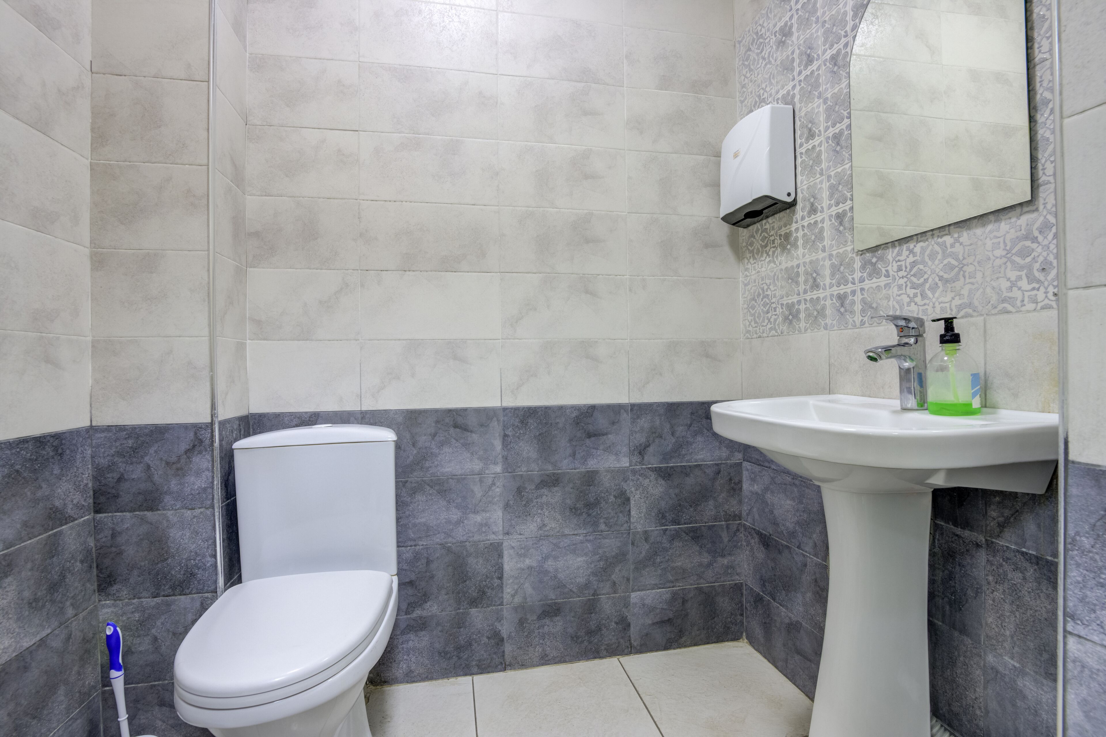 Un baño con inodoro, lavamanos y secamanos.