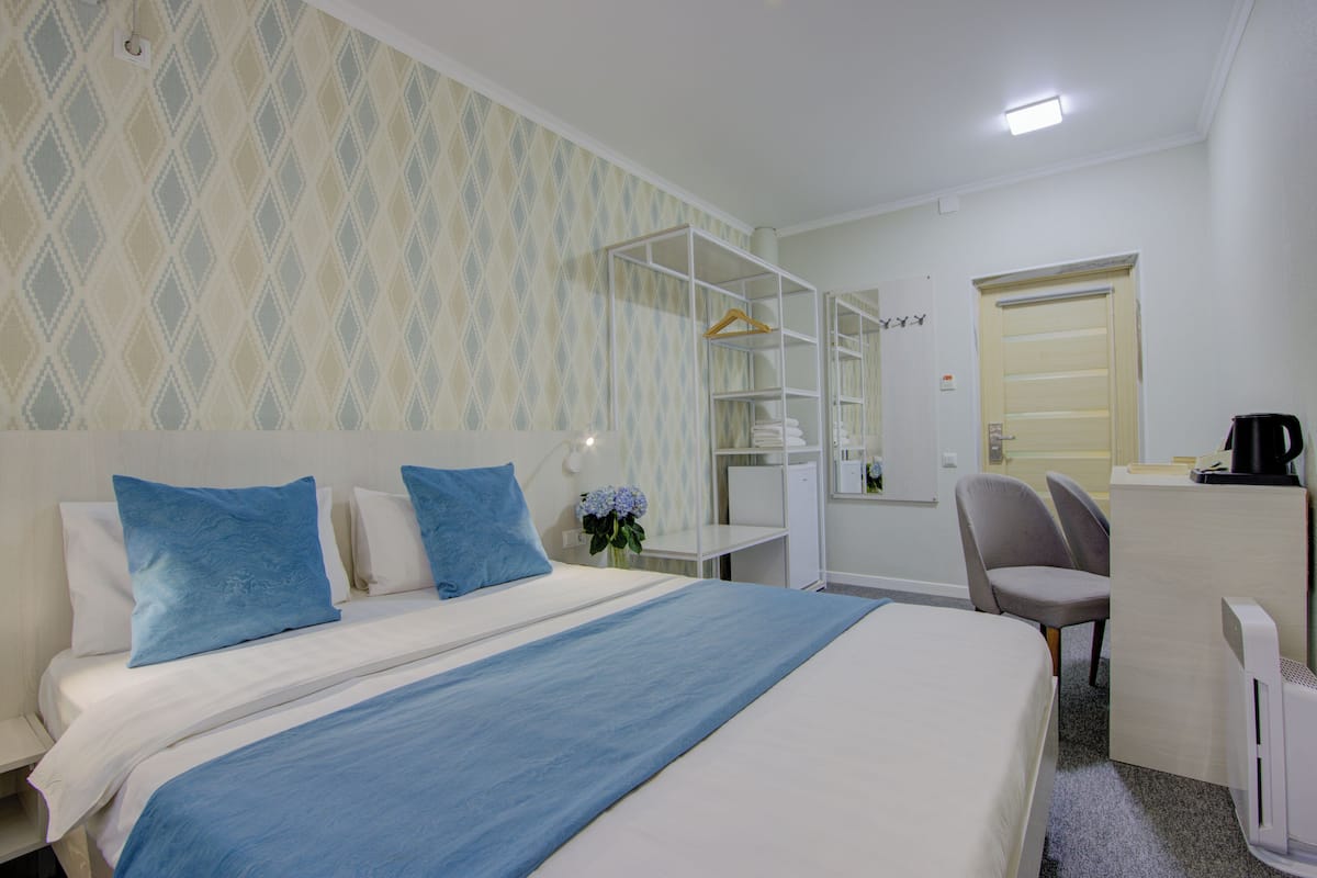 Una habitación de hotel con cama, escritorio, silla, armario y radiador.