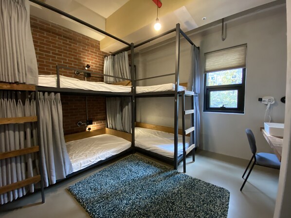 A dormitory room with bunk beds, a brick wall, a window, a desk, and a chair. - Shui Hostel (Busan)