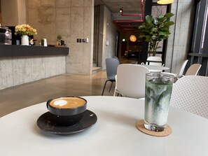 A table with a coffee cup and a glass of iced water in a modern cafe setting. - Shui Hostel (Busan)