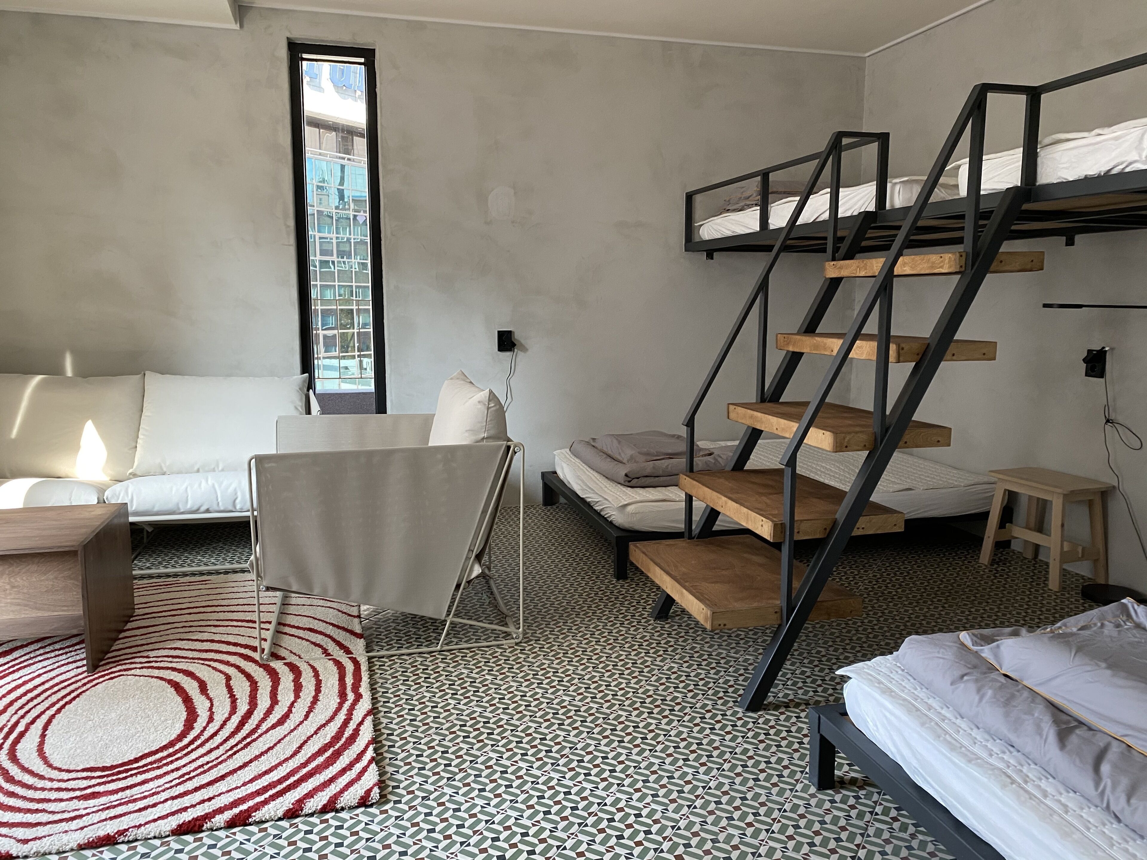 A compact room with a bunk bed, a sofa, a small table, and a patterned rug.