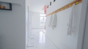 A bright, clean hallway with a coat rack and a shelf with a can of Nivea. - Capsule inn Bali (Legian)