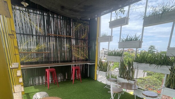 An indoor space with artificial grass, wooden and metal furniture, and potted plants. - Capsule inn Bali (Legian)