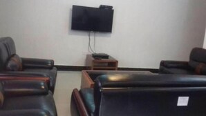A room with two leather sofas, a flat-screen TV mounted on the wall, and a small wooden table with a remote control. - Paramount Luxury Serviced Apartment (Lagos)