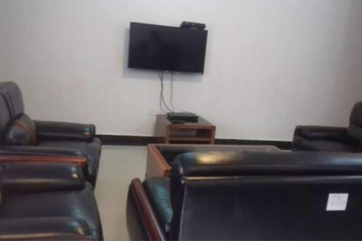 A room with two leather sofas, a flat-screen TV mounted on the wall, and a small wooden table with a remote control.