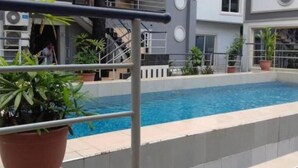 A swimming pool with a metal railing, surrounded by potted plants and a building with a modern design. - Paramount Luxury Serviced Apartment (Lagos)
