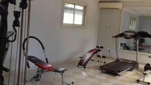 A gym with exercise equipment including a treadmill, weight bench, and resistance machines. - Paramount Luxury Serviced Apartment (Lagos)