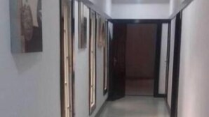 A hallway with a tiled floor, framed artwork on the walls, and a door at the end. - Paramount Luxury Serviced Apartment (Lagos)