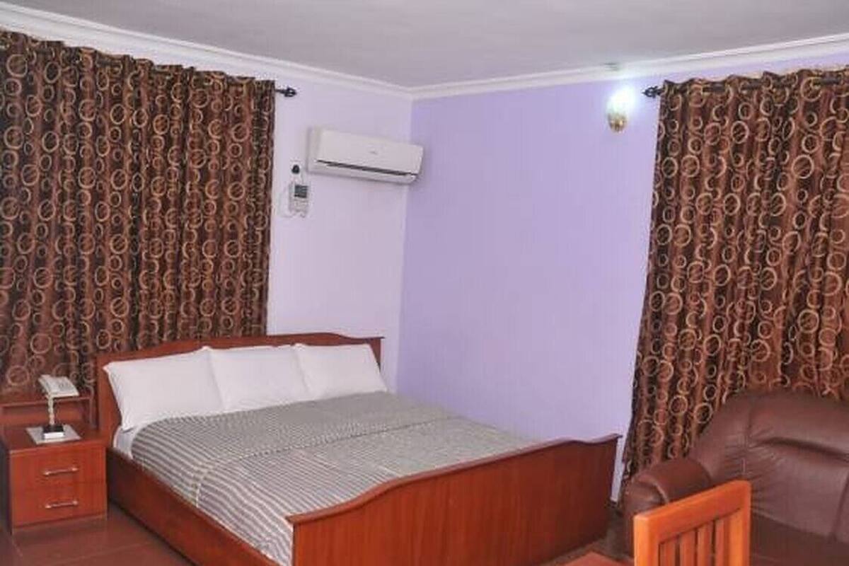 A bedroom with a wooden bed, a nightstand, a chair, and a sofa.