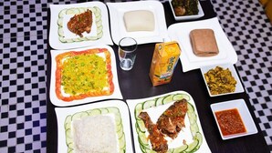 A table with various dishes, including rice, fish, and a juice box. - Eeyilobe Guest House (Lagos)