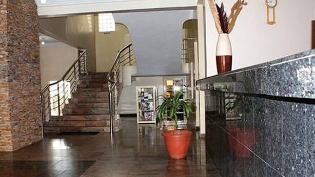 A lobby with a marble reception desk, a staircase, and a potted plant. - Dmatel Hotel and Resort (Lekki)