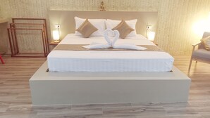A large bed with a headboard, two bedside lamps, and a decorative swan pillow arrangement.