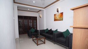 A modern living room with two black sofas, a wooden coffee table, and a TV stand. - Villa304 (Galle)