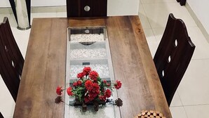 A dining table with a glass partition, wooden chairs, and a flower centerpiece. - Villa304 (Galle)