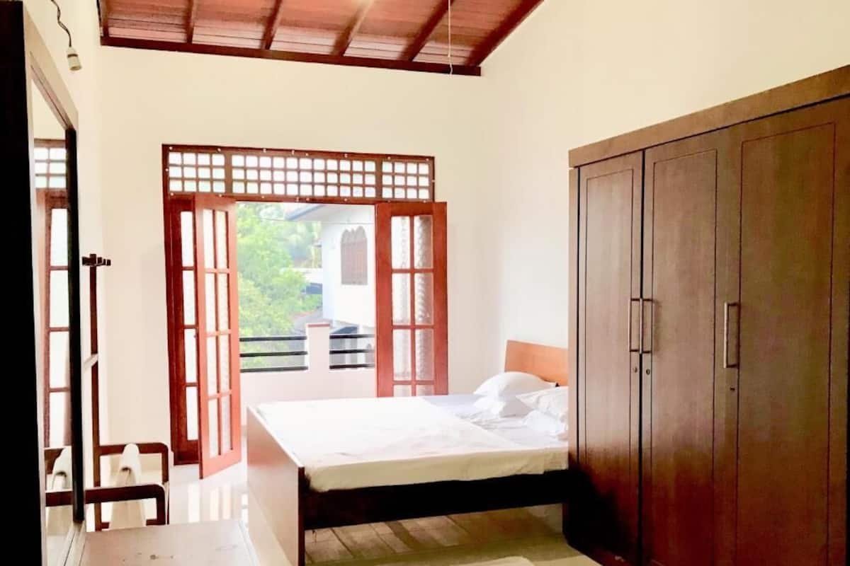 Un dormitorio con cama, armario de madera y vistas a través de una puerta de madera.