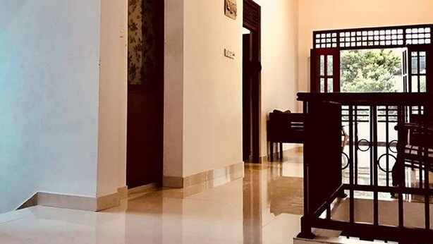 A hallway with a polished floor, a wooden door, and a gate leading to an outdoor area. - Villa304 (Galle)