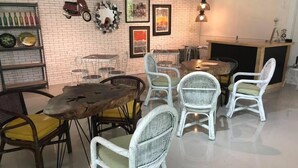 A dining area with wicker chairs, a wooden table, and a brick wall with artwork. - Balconahe Resto Camp (Antipolo)