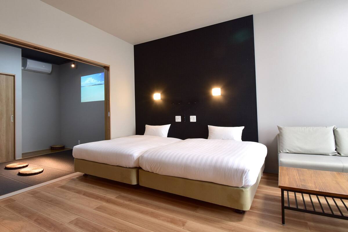 Ein modernes Schlafzimmer mit einem großen Bett, einer Couch und Holzboden.