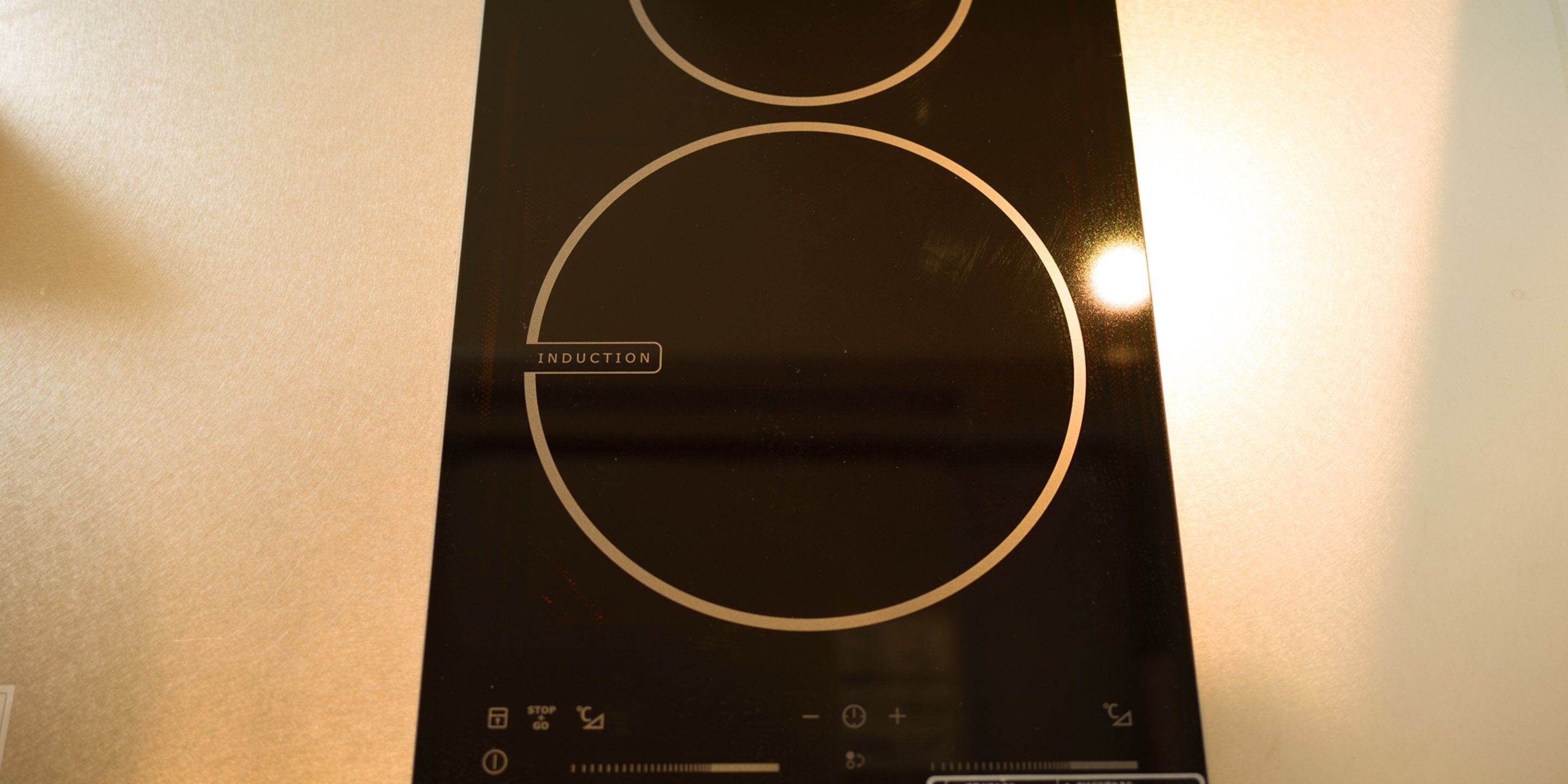 A black induction cooktop with a circular control panel and a "STOP" button.