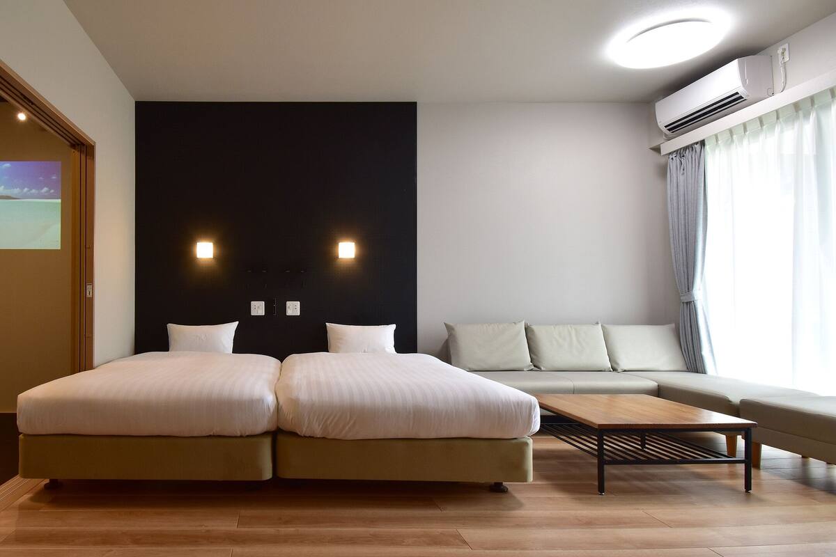 Ein modernes Hotelzimmer mit einem großen Bett, einer Couch und einem flachbildfernseher an der Wand.