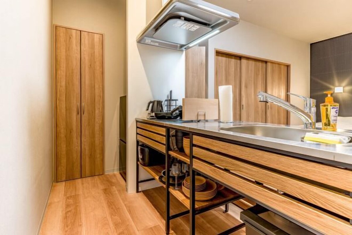 Une cuisine moderne avec des meubles en bois, un évier en acier inoxydable et un four encastré.