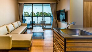 A modern living room with a sofa, a coffee table, and a kitchen area with a sink and a flat-screen TV. - Rakuten STAY MOTEL Kujukurihama Katakai (Kujukuri)