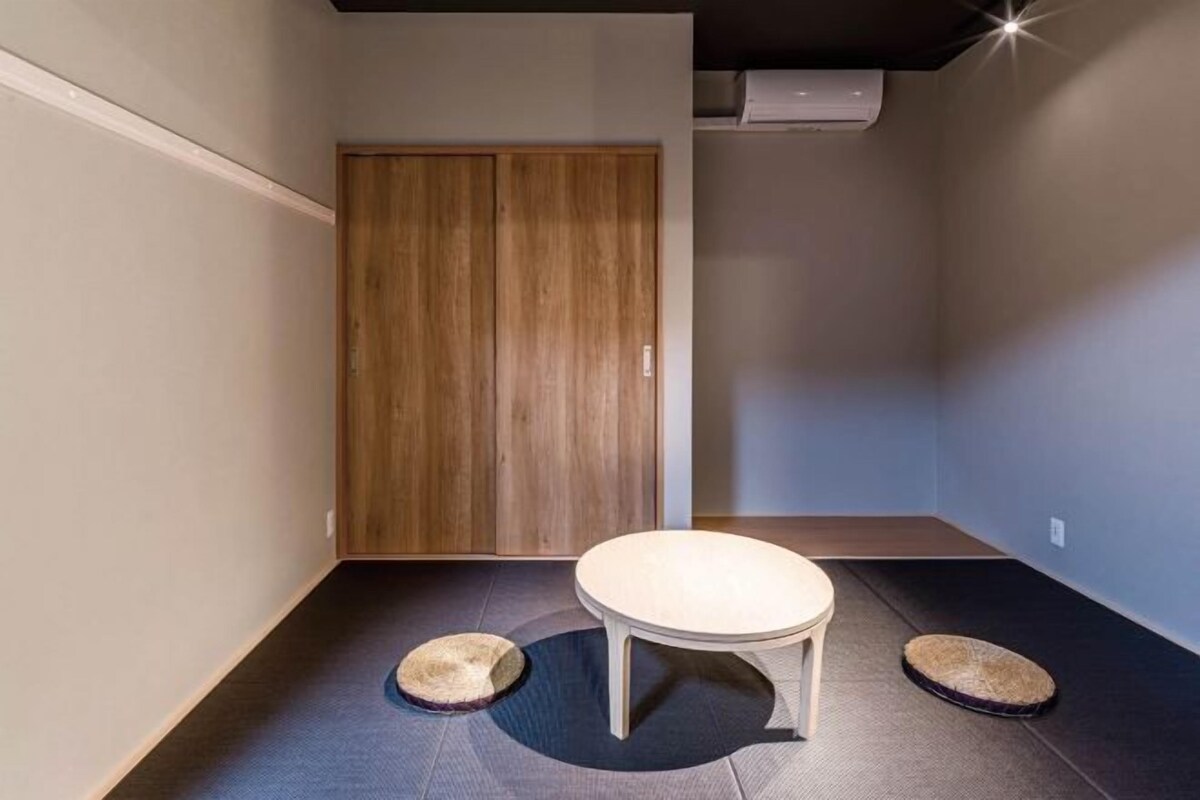 Una habitación pequeña y moderna con un armario de madera, una mesa redonda y dos camas para mascotas.