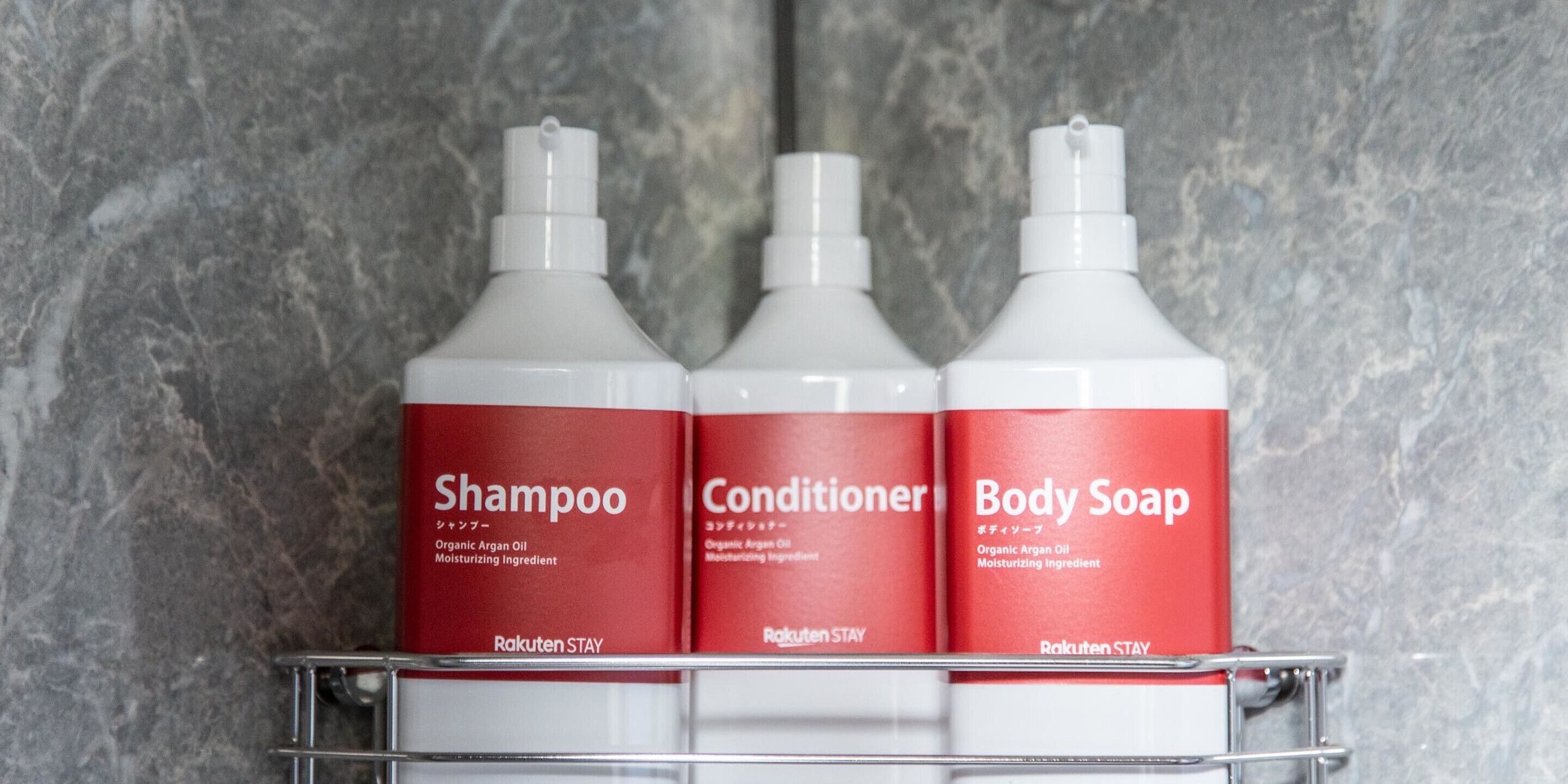 Tre flaconi di prodotti per l'igiene personale Rakuten STAY in un bagno.