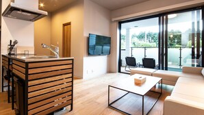 A modern living room with a sofa, a coffee table, and a kitchen area with a sink and cabinets.