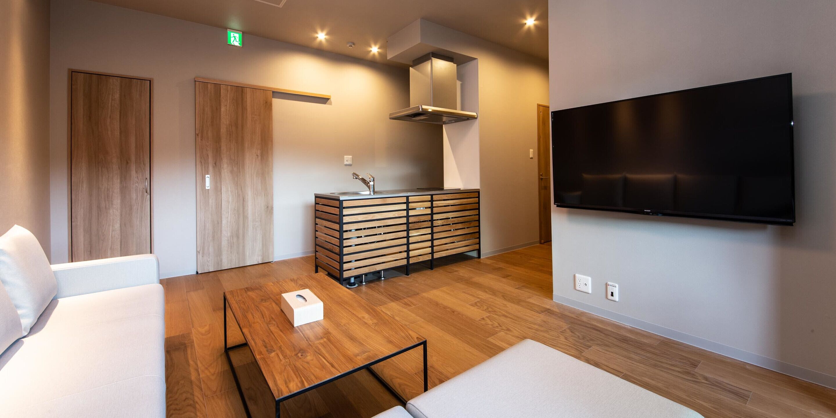 Un salon moderne comprenant un canapé, une table basse, un téléviseur fixé au mur et un meuble en bois.