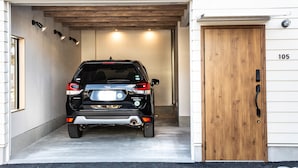 A black SUV parked inside a garage with a wooden door and the number 105 on it.