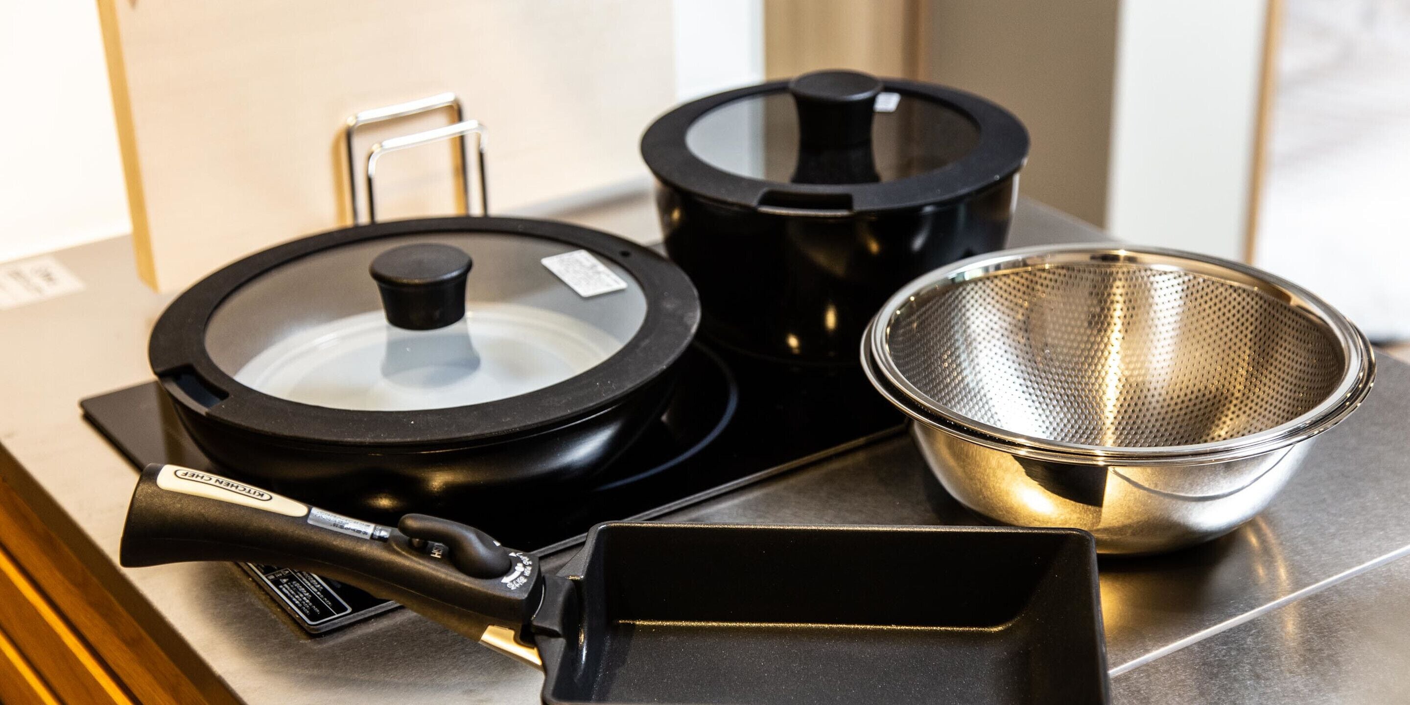 A kitchen with a stove, a kettle, and a colander on a countertop.