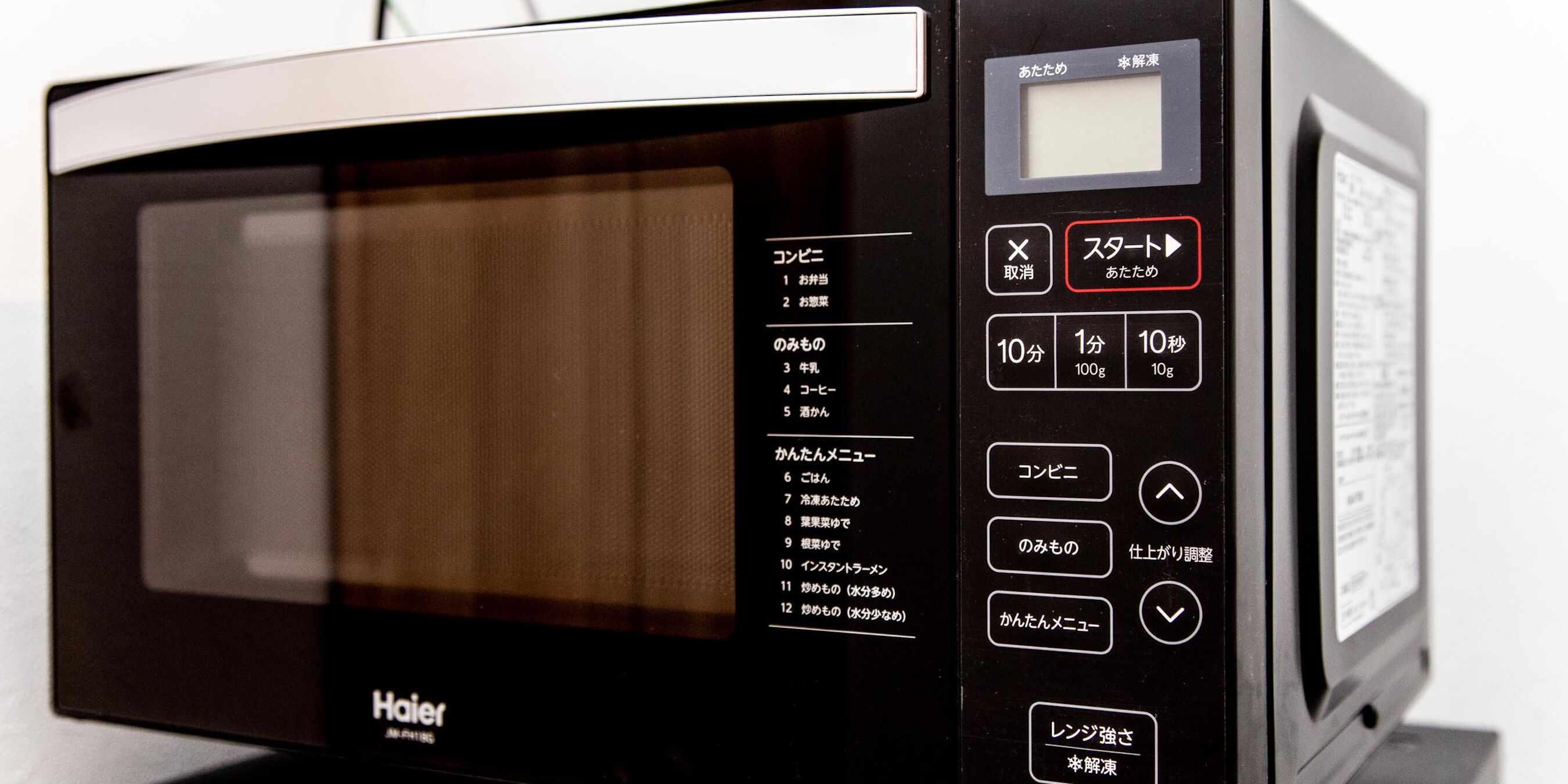A black and silver microwave with a digital display and a control panel with Japanese text.