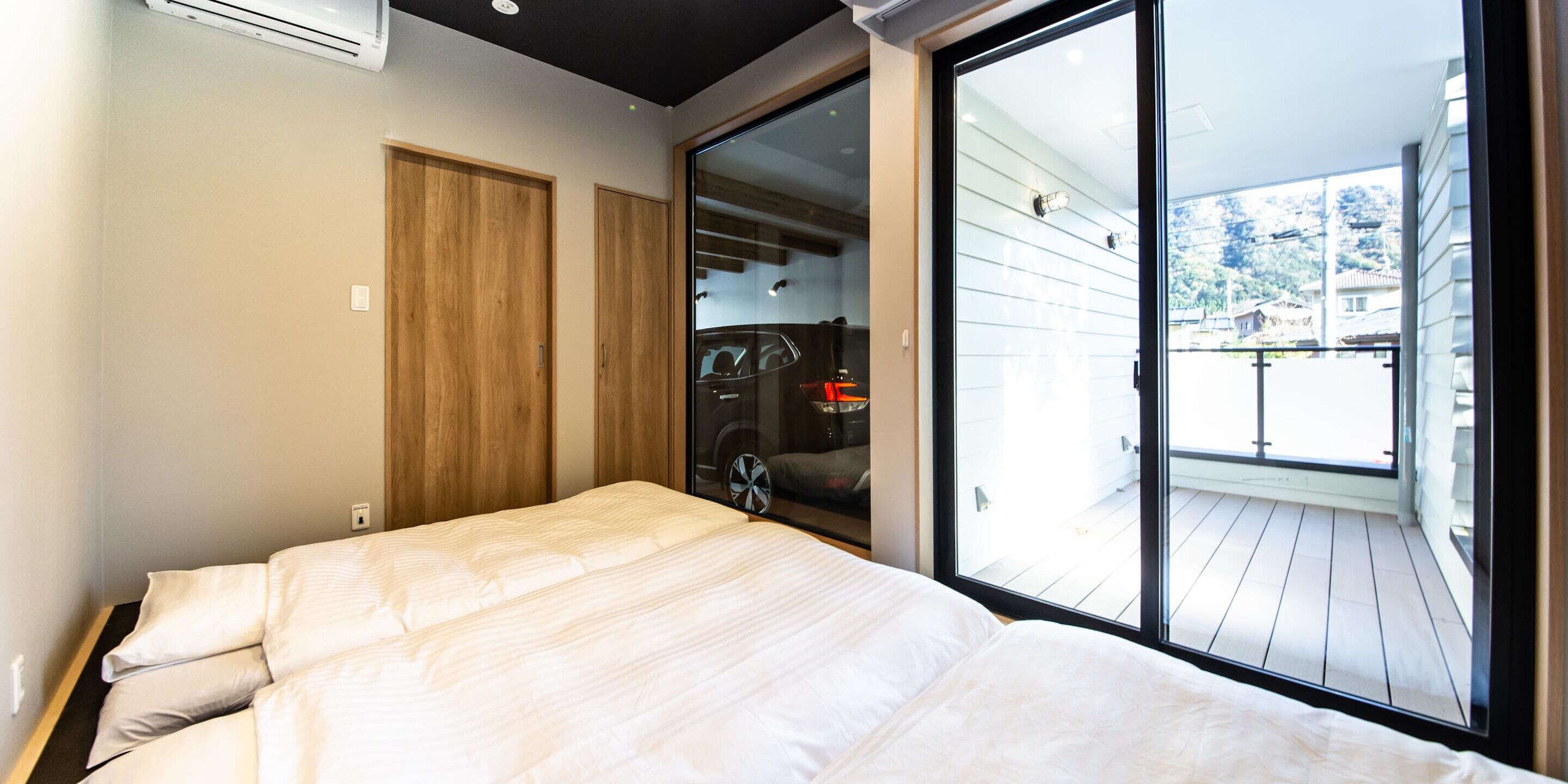 A bedroom with a bed, wooden wardrobe, and a sliding glass door leading to a balcony.