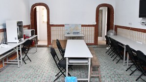 A conference room with a white table, black chairs, a map on the wall, and a clock. - Tumbler Travel (Jinning)