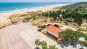 An aerial view of a coastal resort with a beach, a pavilion, and a parking area. - Tumbler Travel (Jinning)