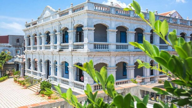 A multi-story building with a classical architectural style, featuring arched windows and balconies. - Tumbler Travel (Jinning)