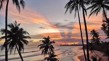 Na praia, areia branca, barracas de praia de cortesia, espreguiçadeiras 