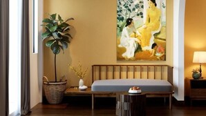A room with a ceiling fan, a large painting, a bench, a potted plant, and a lamp. - Chez Mimosa Local Homestay (Ho Chi Minh City)